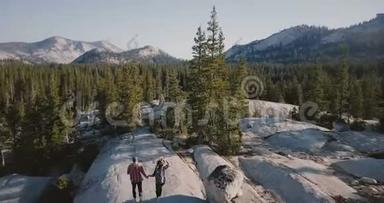 无人机镜头跟随年轻的快乐夫妇一起奔跑，一起在令人惊叹的白色岩石上<strong>徒步走</strong>向史诗般的约塞米蒂公园天际线。